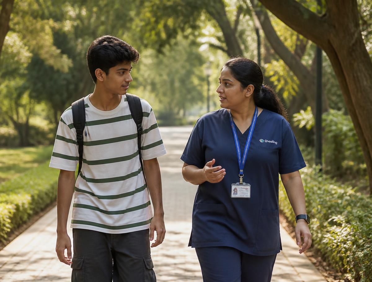 A young person and a practitioner walking and talking together along a leafy park path